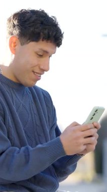 Genç adam akıllı telefonuna çift ekran kompozisyonu ile bakarken bir dizi duyguyu deneyimliyor. Dikey görüntüler