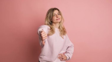 Yavaş çekimde, pembe arka planda, kendine güvenen bir sarışının parmak ucunda anlaşmazlık gösteren bir stüdyo videosu.