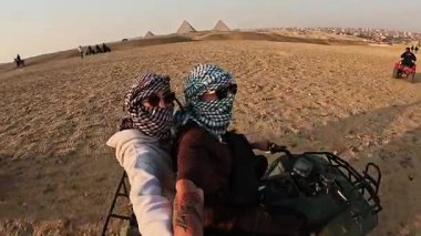 Efsanevi giza piramitlerinin yanında dörtlü bisiklete binerken çöl heyecanı yaşayan maceraperest turistler yaz tatilinde nefes kesici Mısır manzaraları yakalıyorlar.