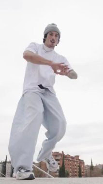 Kentsel çatıda atletik hareketleri kıran genç bir erkeğin dinamik dans performansı, serbest stil hip hop sanatını çağdaş hareket ve kentsel tarzla harmanlıyor.