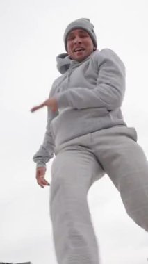 Kendine güvenen genç erkek dansçı şehir manzarasına karşı dinamik enerjiyle serbest dans ederek sokak dansı stilinde tutkuyu ifade ediyor.