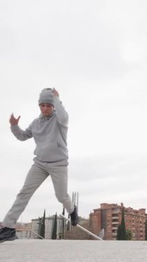 Endüstriyel şehir manzarasına karşı dinamik hareketleri mükemmelleştiren genç break dansçı güçlü atletik enerji ve yaratıcı ifade ile tutkulu sokak dansı becerisi sergiliyor.