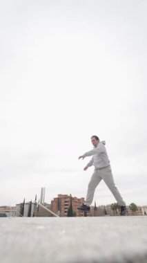 Breakdansçı zor bir dondurucu duruşta dengede duruyor, atletik hüner ve şehir mimarisine karşı sokak dansı becerisi gösteriyor.