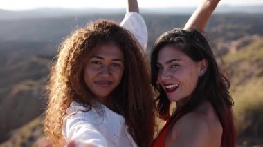 Neşeli çoklu etnik kadınlar dramatik çöl kanyonu manzarasına karşı selfie anı yakalıyorlar, dostluk ve seyahat maceraları sergiliyorlar.