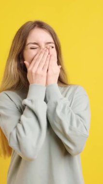 Sarışın kadın, hayat dolu sarı bir zemin karşısında kahkaha ve mutluluk gibi çeşitli duygular sergiliyor.