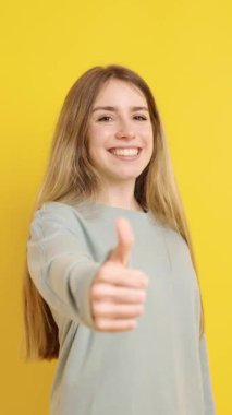 Sarı arka planda onay, anlaşma ya da destek gösteren olumlu genç kadın