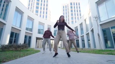 Üç kadın dansçı modern bir mimari mekanda koreografiyle dans ediyorlar.