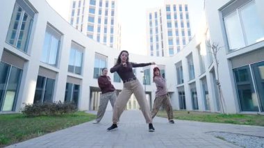 Dinamik dans ekibi modern kentsel mimari fon, gösteri ekibi ve yaratıcı enerji karşısında senkronize hip hop performansı sergiliyor.