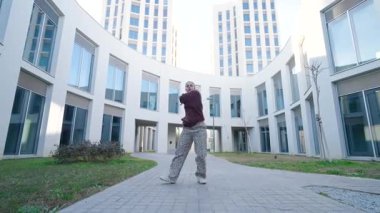 Şehir dansçısı, modern mimari arkaplana karşı dinamik bir performansta akışkan hareketler sergiliyor.