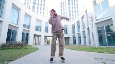 Dinamik dansçı, çağdaş şehir arkaplanına karşı serbest dans hareketleri sergiliyor, tutkulu sanatsal hareketi enerjik ritim ve stil ile ifade ediyor