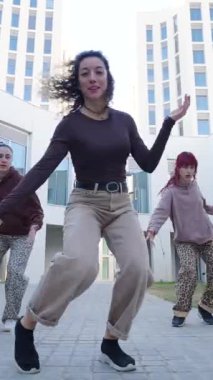 Genç bayan dansçılar şehir merkezindeki dinamik sokak dansı hareketleri yoluyla enerji ve yaratıcılıklarını ifade ederek senkronize koreografi yapıyorlar.