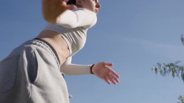 Yaratıcı enerjisini dinamik modern dans performansıyla ifade eden yetenekli profesyonel dansçı canlı mavi gökyüzü arka planına karşı.