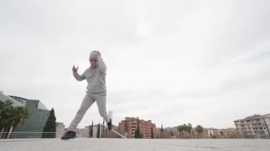 Breakdance sanatçısı dinamik güç hareketleri gerçekleştiriyor ve şehir manzarasına karşı teknikleri donduruyor, beceri ve sanatsal ifade sergiliyor