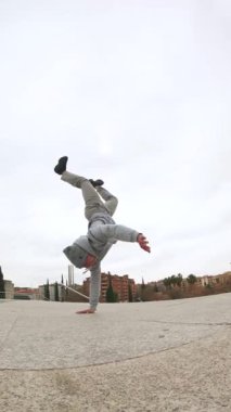 Yetenekli break dansçı bir amuda kalkıyor, güç ve denge gösterisi sergiliyor.