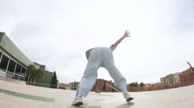 Becerikli break dansçılar dinamik sokak dansı hareketleri yapıyor, güç, yaratıcılık ve şehir manzarasında atletik maharet sergiliyorlar.