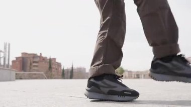 Modern koreografi üzerine çalışan genç erkek dansçı, dinamik enerji ve yaratıcı tutku ile kentsel binaların yakınında sanatsal hareketleri ifade ediyor.