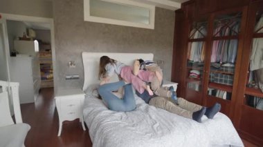 Sevgi dolu ebeveynler, küçük kızlarını keyifle kaldırır ve rahat bir yatak odasında oynarlar. Neşeli aile anlarını ve bağlantılarını paylaşırlar.