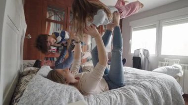 Aile üyeleri neşe içinde oynuyorlar, zıplıyorlar ve birlikte gülüyorlar. Parlak, rahat bir yatak odasında, gerçek mutluluk anlarını ve aile bağlarını paylaşıyorlar.