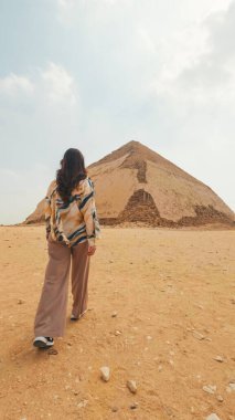 Çölde yürüyen bir turist eğri piramide doğru yürüyor. Yıldız çiçeğinin kraliyet mezarlığında bulunan eski bir Mısır kraliyet mezarı.