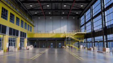 Güneş ışığı boş bir deponun içini aydınlatıyor. Geniş ve endüstriyel tasarımını sergiliyor.