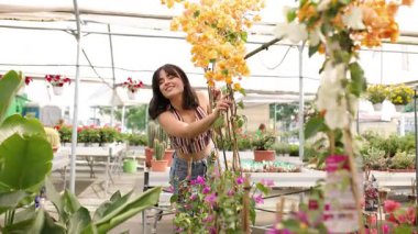 Çocuk odasını keşfeden mutlu genç bir kadın çiçeklere dokunuyor.