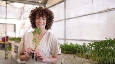 Gülümseyen kadın bahçıvan elinde tohumlarla seranın içinde