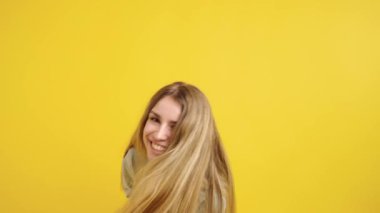 Neşeli, genç bir bayanın neşeli ve neşeli duygularını ifade edişinin görüntüsü, canlı sarı bir arka planda izole edilmiş.