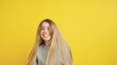 Kadın, neşeli duygular sergiliyor, kahkahadan sürprize, canlı sarı bir arkaplan üzerine kurulmuş. Mutluluk ve heyecanın özünü yakalar.