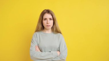 Stüdyo portresi çekilirken çok çeşitli duygular besleyen genç bir kadın canlı sarı arka plana karşı nüanslı yüz ifadeleri yakalıyor.