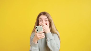 Genç bir kadının akıllı telefonuna şaşkınlık, kahkaha ve heyecanla tepki verdiği görüntüler.