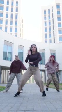 Şehir ortamında senkronize hareketlerini sergileyen dört kadın dansçı dinamik bir sokak dansı gösterisi yapıyorlar.