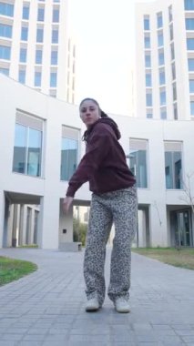 Profesyonel dansçı modern mimari arkaplana karşı dinamik kent dansı hareketleri sergiliyor, güçlü hareket ve sokak dansı tarzıyla yaratıcı enerjiyi ifade ediyor.