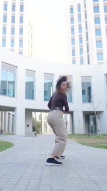 Kıvırcık saçlı, modern dinamik koreografi yapan modern dansçı. Şık mimari yapının yanında. Ritmik hareketlerle yaratıcı enerjiyi ifade ediyor.