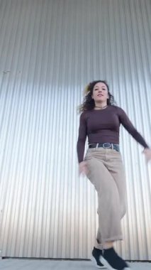 Dinamik kadın dansçı cesur endüstriyel metal duvara karşı yaratıcı enerjisiyle serbest dans ederek bireysel sanatsal tutkusunu ritmik hareketlerle ifade ediyor.