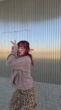 Kendine güvenen kadın dansçı modern dans rutinini mükemmelleştiriyor, sanatsal hareketleri göstererek metalik arka planda gelişigüzel kentsel tarzda sanatsal hareketleri ifade ediyor.