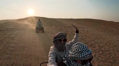 Turistler gün batımında Giza Piramitleri 'nin yakınlarındaki çöl manzarasını keşfederek dört tekerlekli bisiklet macerasının tadını çıkarıyorlar.