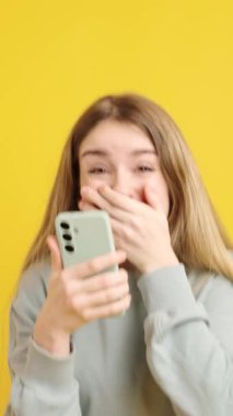 Kolaj, genç ve neşeli bir kadının canlı sarı bir arka plana karşı akıllı telefonuyla etkileşimini gösteriyor.