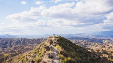 Bir dağ sırtında duran yürüyüşçü İspanya 'nın çorak topraklarının panoramik manzarasının tadını çıkarıyor.