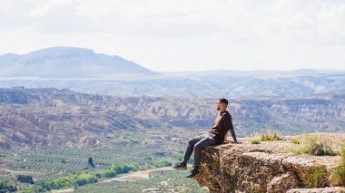 Uçurumda oturan bir turist, İspanya 'nın büyüleyici manzarasını seyrediyor, doğanın enginliğinin tadını çıkarıyor.