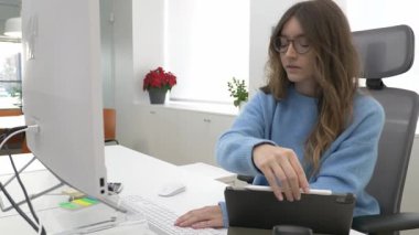Ofis çalışanı çoklu görev, bilgisayar ve tablet kullanarak, çağdaş bir çalışma alanında verimlilik sergiliyor