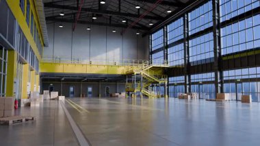 Güneş ışığı büyük, boş bir depoya akar, alanı aydınlatır ve mimari ayrıntıları ön plana çıkarır.