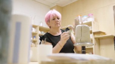 Kıvrımlı kil döşeyen yetenekli bir seramistim atölyesinde çömlek teknikleri gösteriyor.