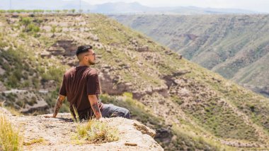 Genç adam bir uçurumda oturmuş, Granada, İspanya 'daki muhteşem megalitik parkın muhteşem manzarasının tadını çıkarıyor.