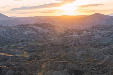 Gorafe çölünde eşsiz çorak arazi oluşumlarının üzerinde batan güneş engebeli arazinin üzerinde sıcak, altın bir parıltı yaratıyor.