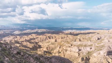 Gorafe Çölü, Granada, İspanya 'daki kurak arazide güneş ışığı ve gölgeli engebeli kanyon üzerinde hareket eden bulutların hızlandırılmış görüntüsü