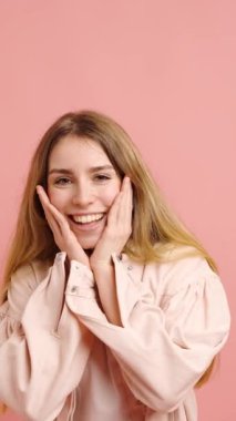 Genç kadın, canlı pembe bir arkaplan karşısında çeşitli şaşkınlık ve neşe ifadeleri sergiliyor.