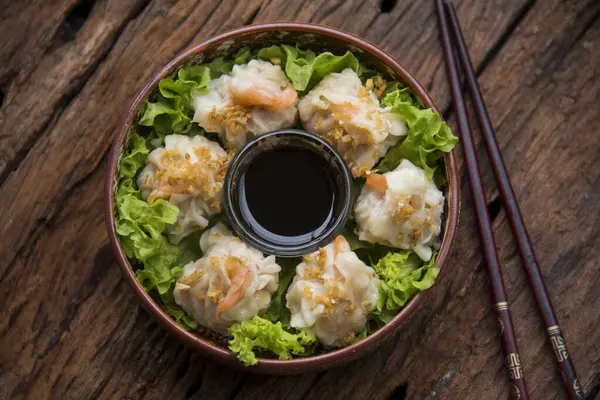 Shumai shrimp with sauce, Steamed shrimp dumplings dim or dim sum and vegetable on wooden table, Cantonese Dimsum food cuisine for breakfast, Chinese traditional food.