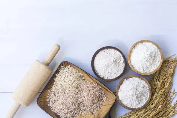 Rice flour in wooden bowl with white rice, Thai  Native rice, rice ears, and paddy ear rice  isolated on white wooden background.