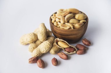 Tahta kaselerdeki fıstıklar kabuklarındaki fıstıklardan bir koleksiyon ve kabuksuz birkaçı protein ve yağ açısından zengin fıstıklardan oluşan sağlıklı abur cubur konsepti, beyaz arka planda izole edilmiş.. 