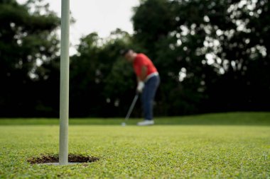 Blurred Golfer putting ball on the green golf, lens flare on sun set evening time. Golfer hitting golf ball. Sport holiday lifestyle Concept.